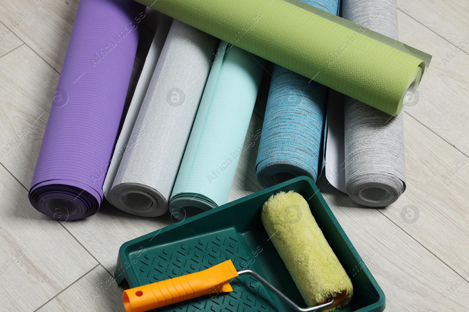 Photo of Different wallpaper rolls, roller and tray on floor