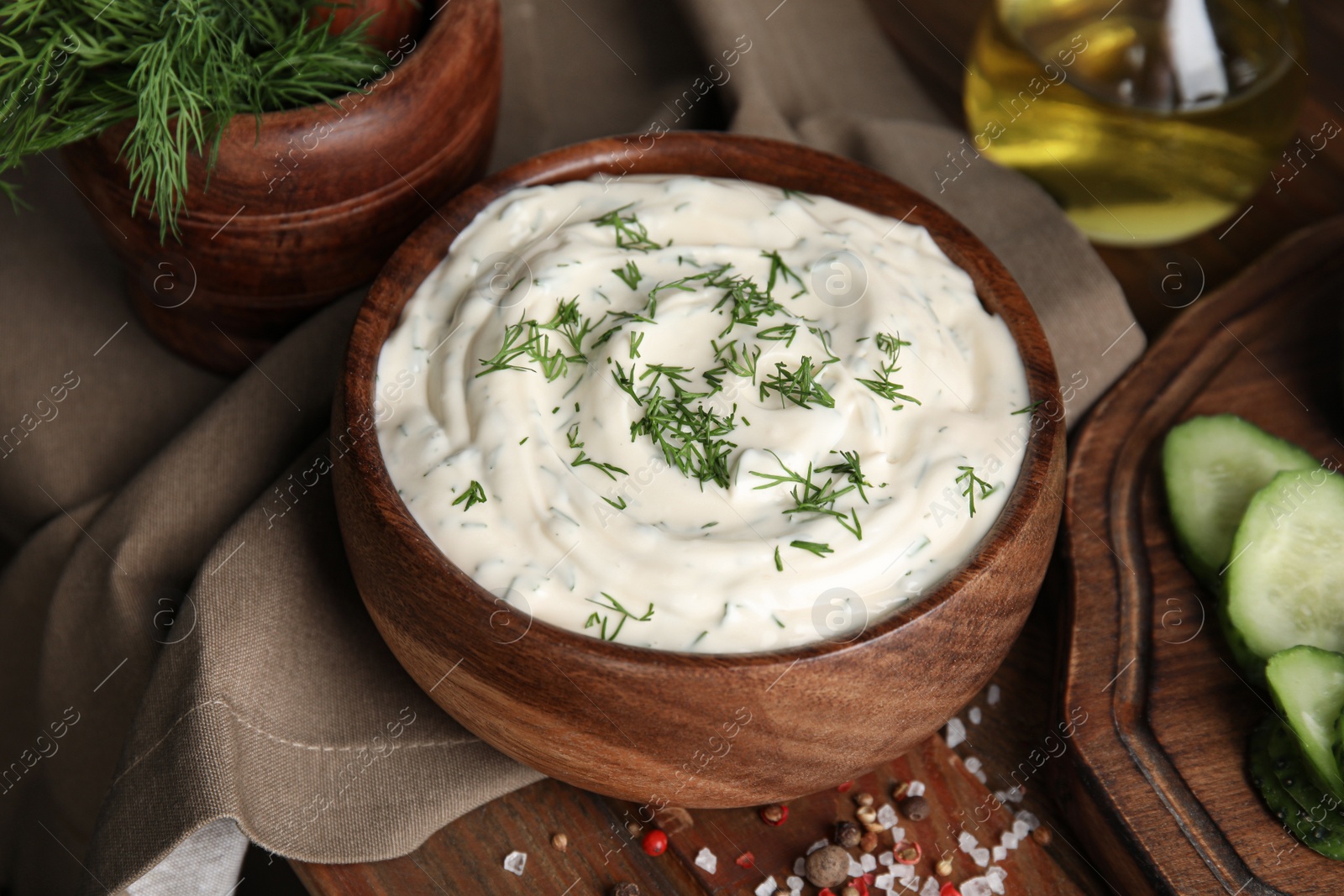 Photo of Tasty creamy dill sauce in bowl on wooden table