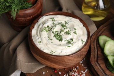 Photo of Tasty creamy dill sauce in bowl on wooden table