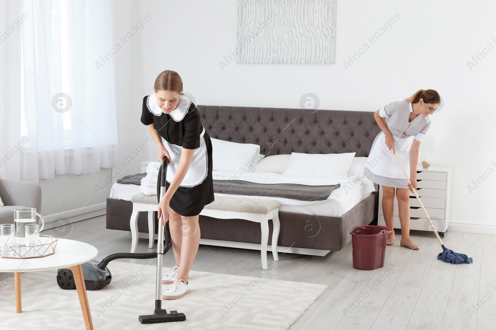 Photo of Professional chambermaids cleaning floor in hotel room