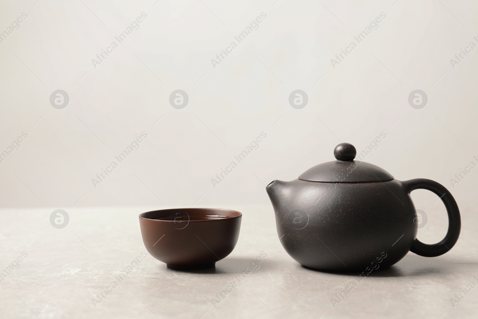 Photo of Cup and teapot with oolong on light background. Space for text