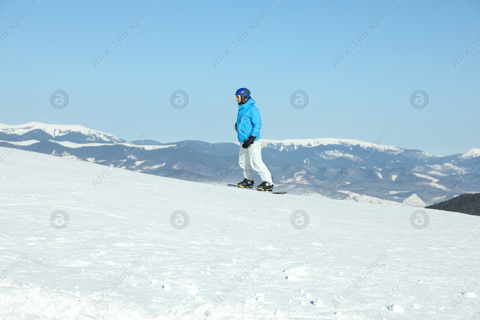 Photo of Male snowboarder on snowy slope in mountains. Winter vacation