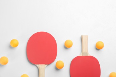 Photo of Ping pong rackets and balls on white table, flat lay. Space for text