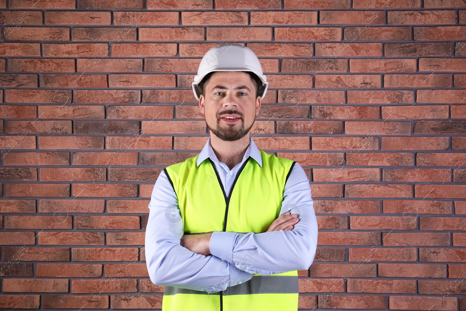 Photo of Male industrial engineer in uniform on brick wall background. Safety equipment