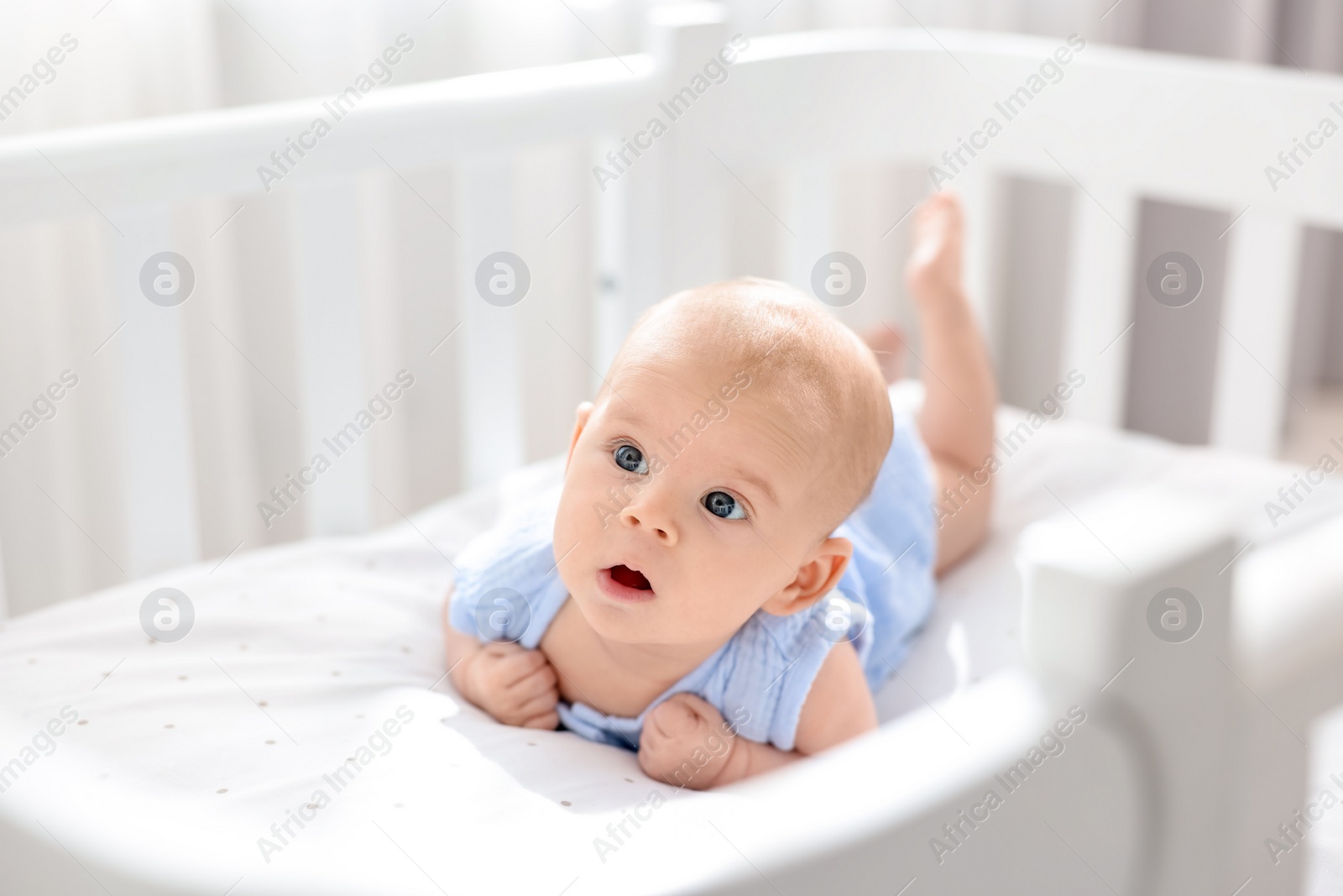 Photo of Cute little baby lying in crib at home, space for text