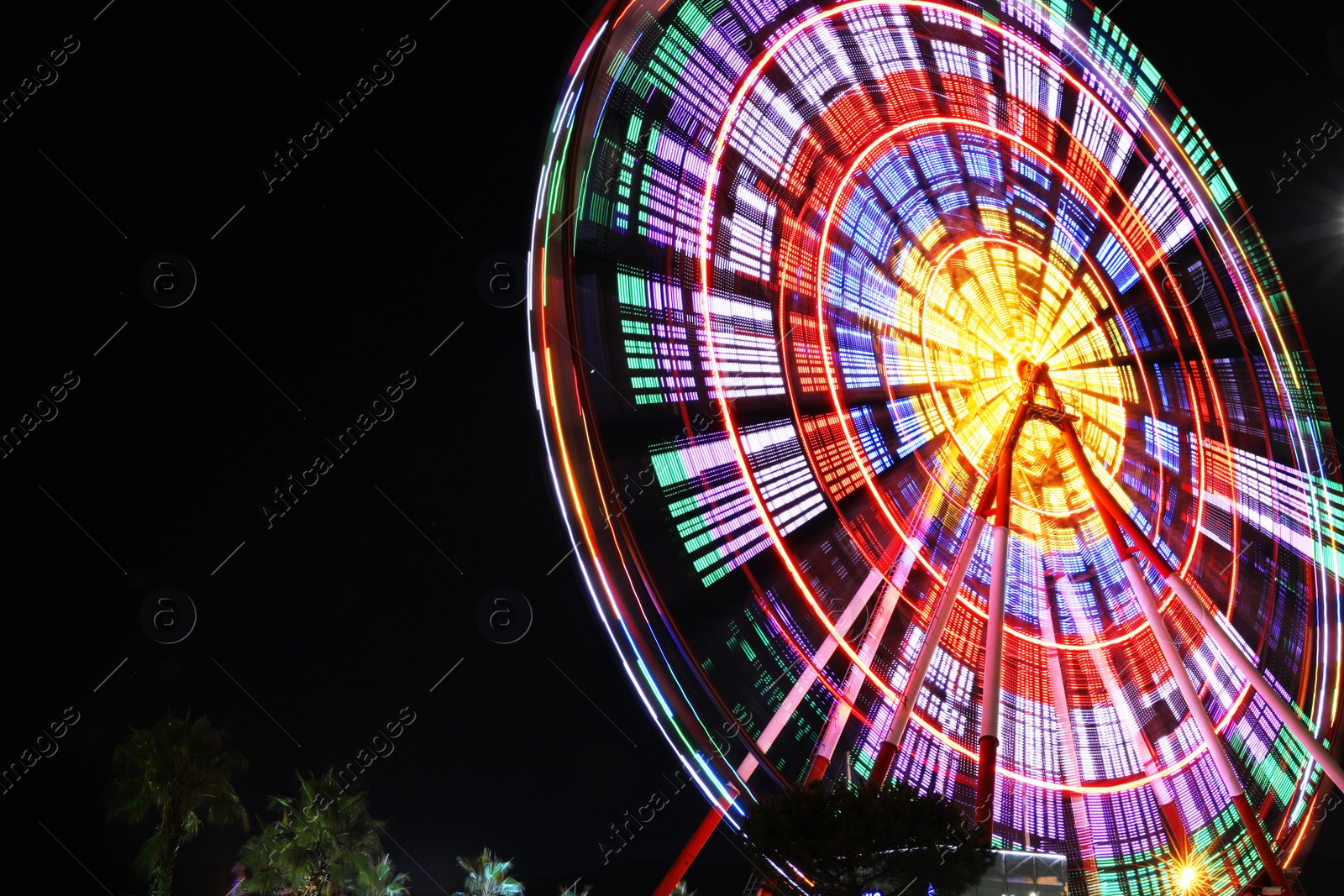 Photo of Beautiful glowing Ferris wheel against dark sky, low angle view. Space for text