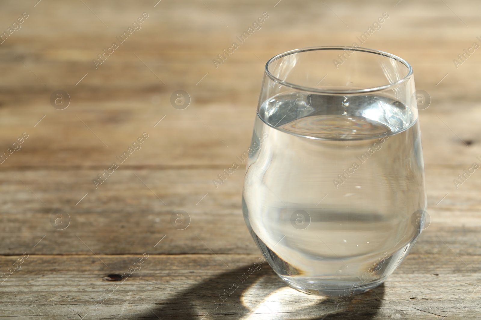 Photo of Glass of water on wooden table, closeup with space for text. Refreshing drink