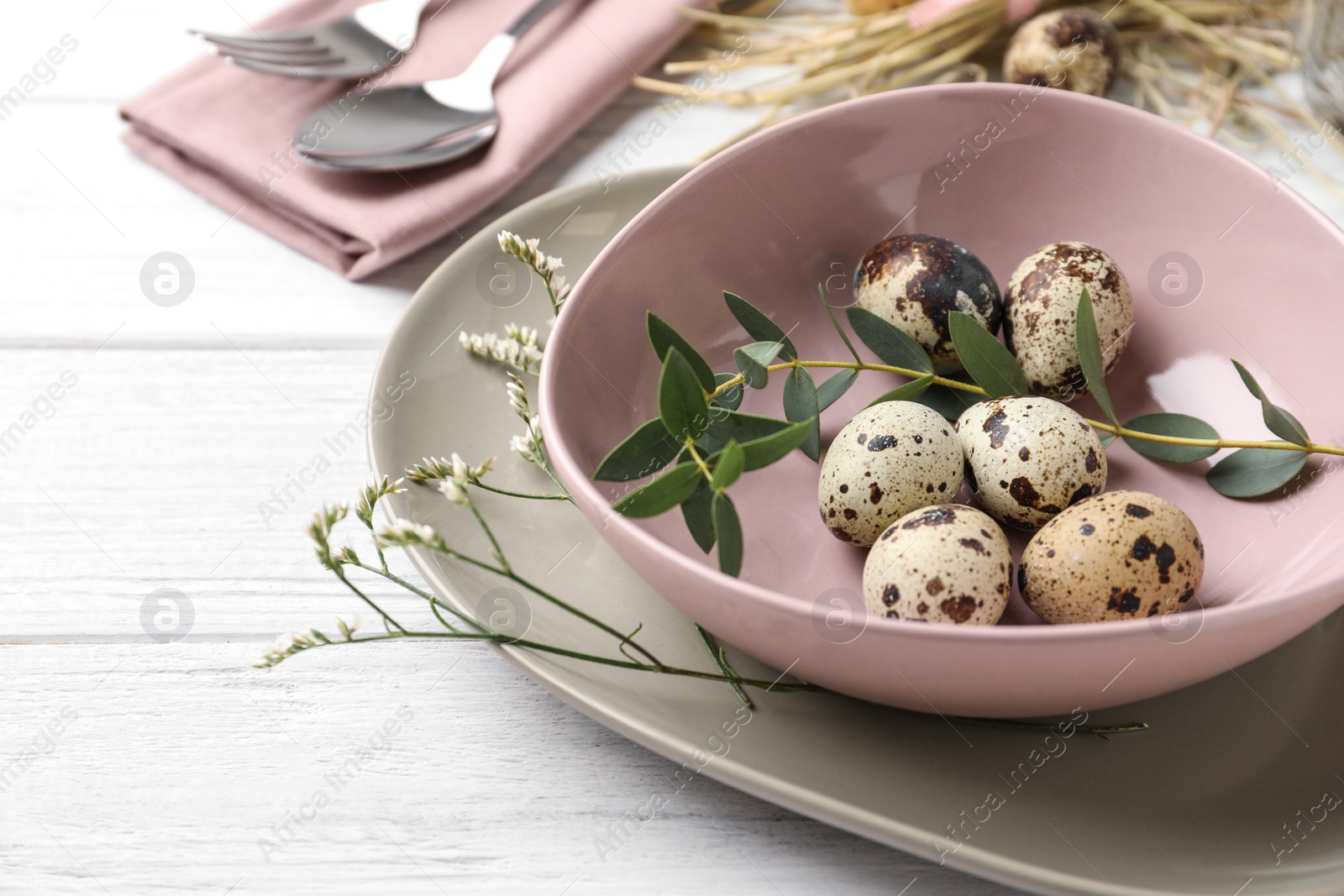 Photo of Festive Easter table setting with quail eggs and floral decor on wooden background, closeup