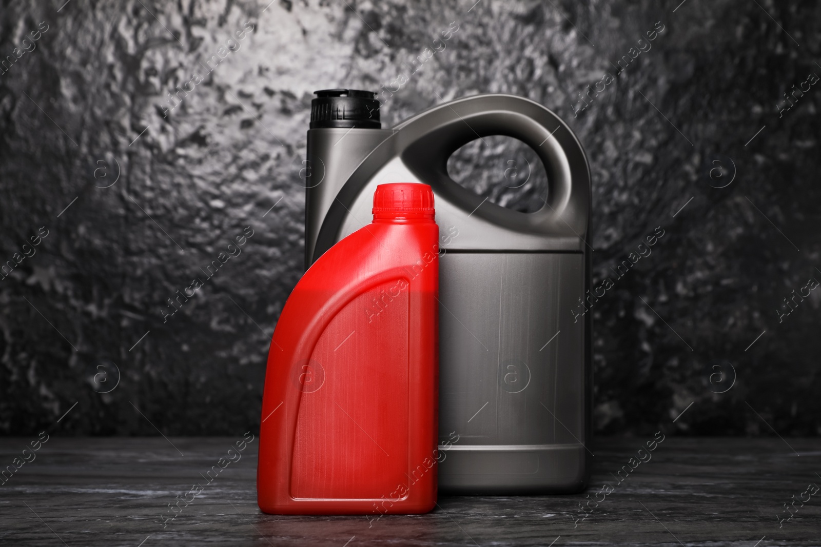 Photo of Motor oil in different canisters on black table near dark wall