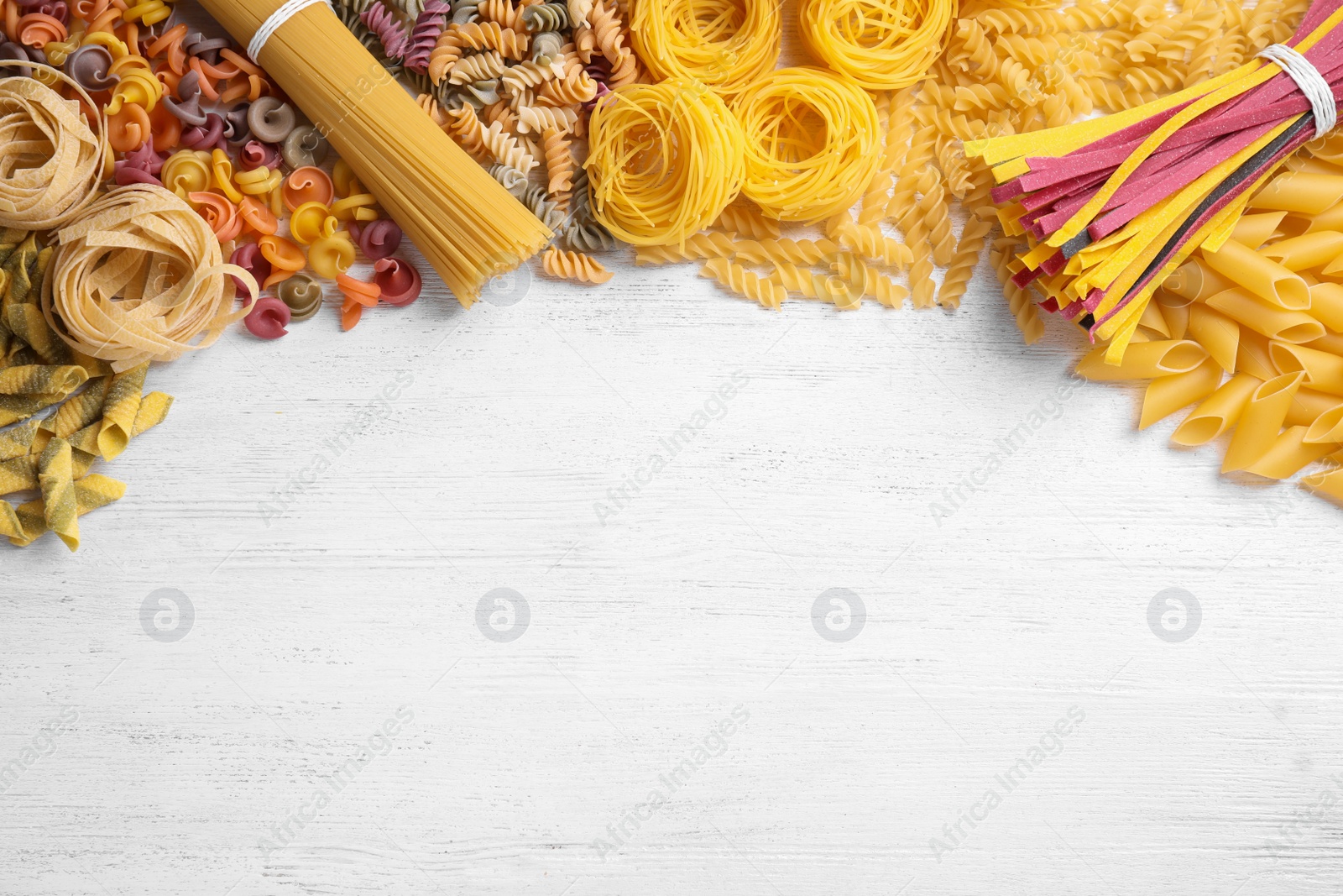 Photo of Different types of pasta on white wooden table, flat lay. Space for text