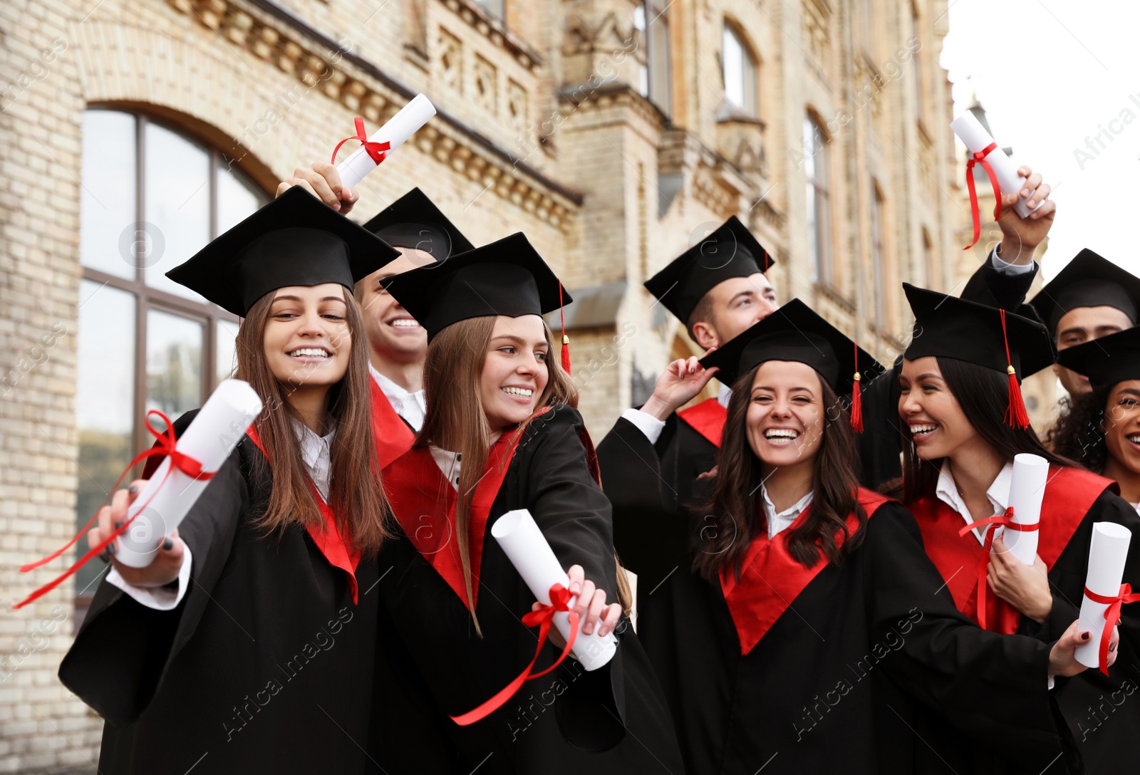 Photo of Happy students with diplomas outdoors. Graduation ceremony