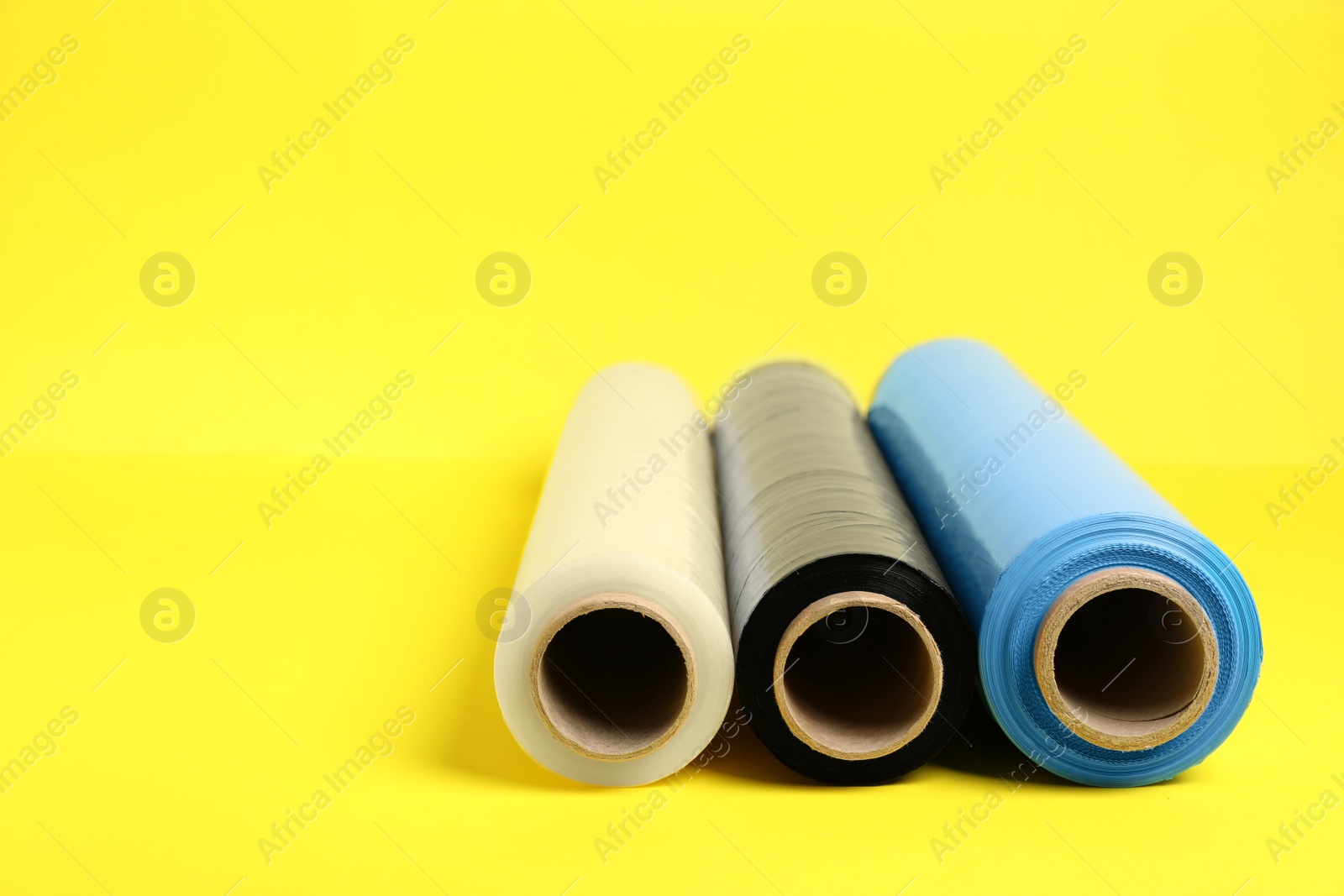 Photo of Rolls of different stretch wrap on yellow background. Space for text