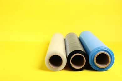 Photo of Rolls of different stretch wrap on yellow background. Space for text