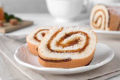 Photo of Tasty cake roll with jam on white table, closeup