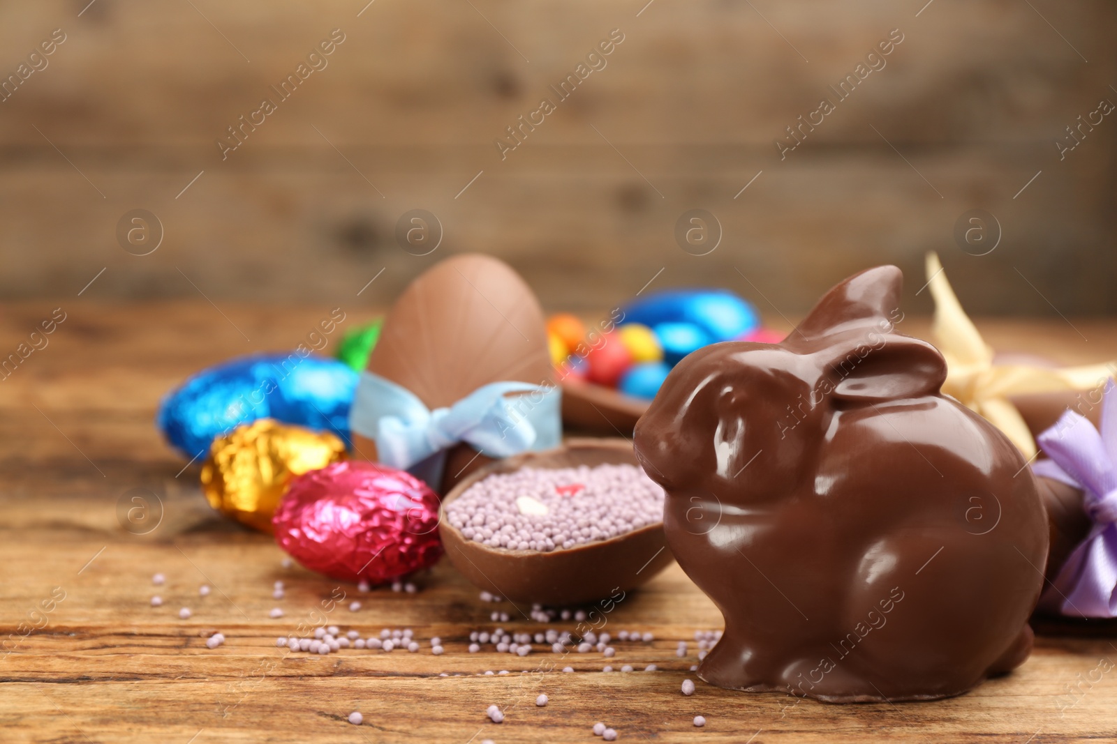 Photo of Chocolate Easter bunny and eggs on wooden table. Space for text