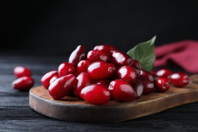 Fresh ripe dogwood berries with green leaf on black wooden table, closeup