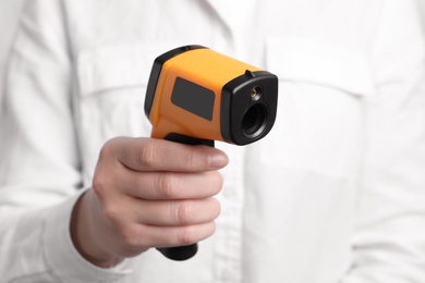 Photo of Woman holding non contact infrared thermometer, closeup