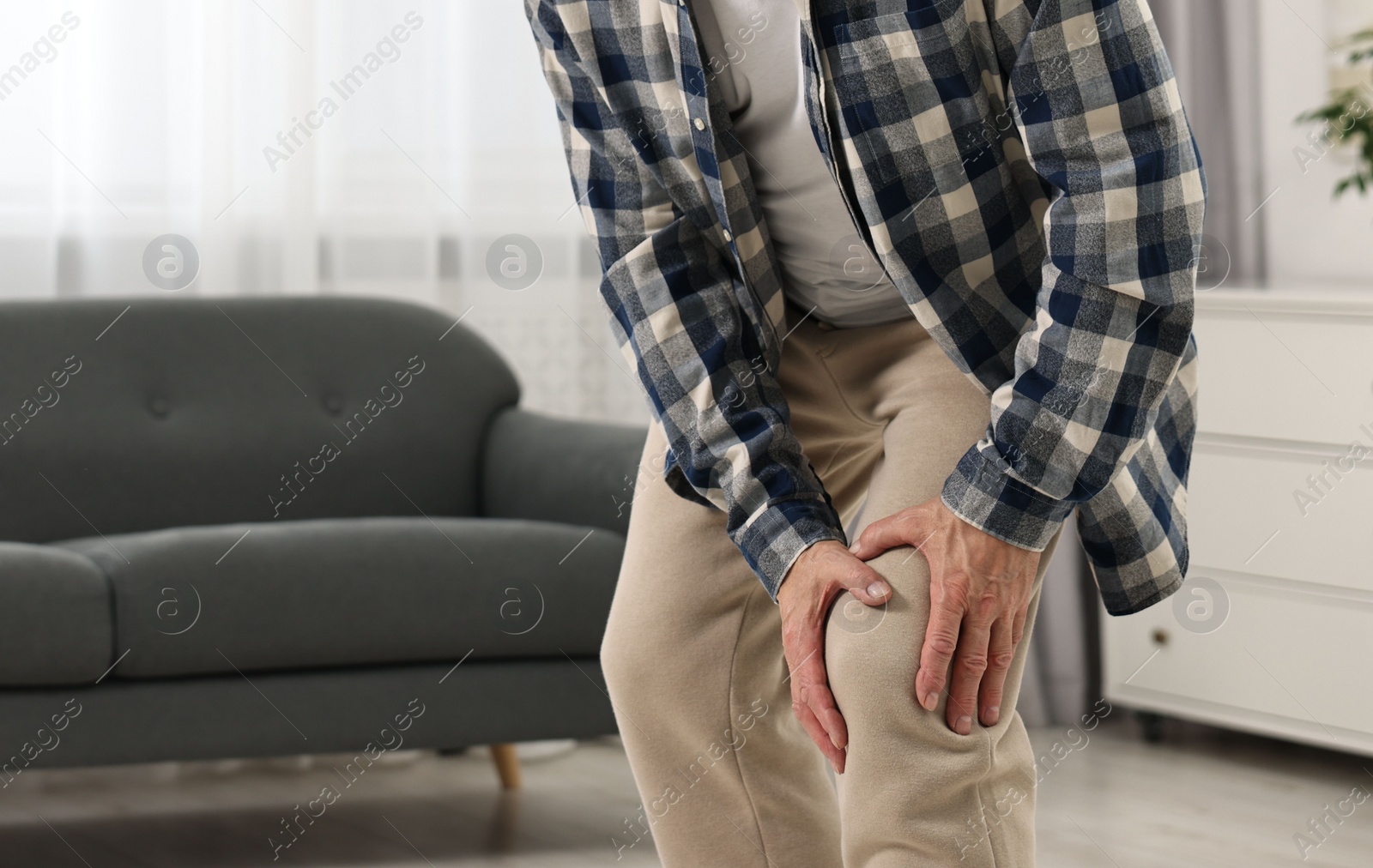 Photo of Arthritis symptoms. Man suffering from pain in knee at home