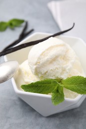 Photo of Delicious ice cream, mint and vanilla pod on light grey table, closeup