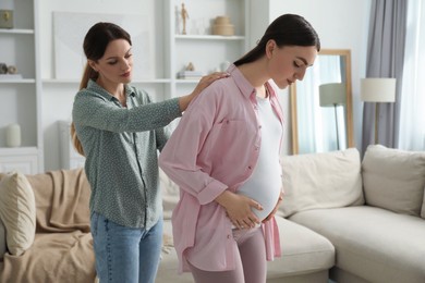 Doula massaging pregnant woman at home. Preparation for child birth