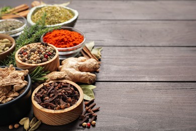 Photo of Different natural spices and herbs on wooden table. Space for text