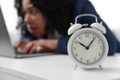 Stressful deadline. Alarm clock near woman working at white desk, selective focus. Space for text