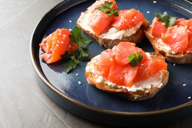 Photo of Tasty bruschettas with salmon, cream cheese and parsley on grey table, closeup