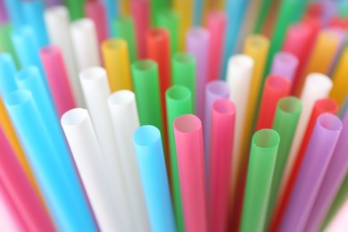 Photo of Heap of colorful plastic straws for drinks as background, closeup