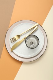 Photo of Ceramic plates, glass and cutlery on color background, top view