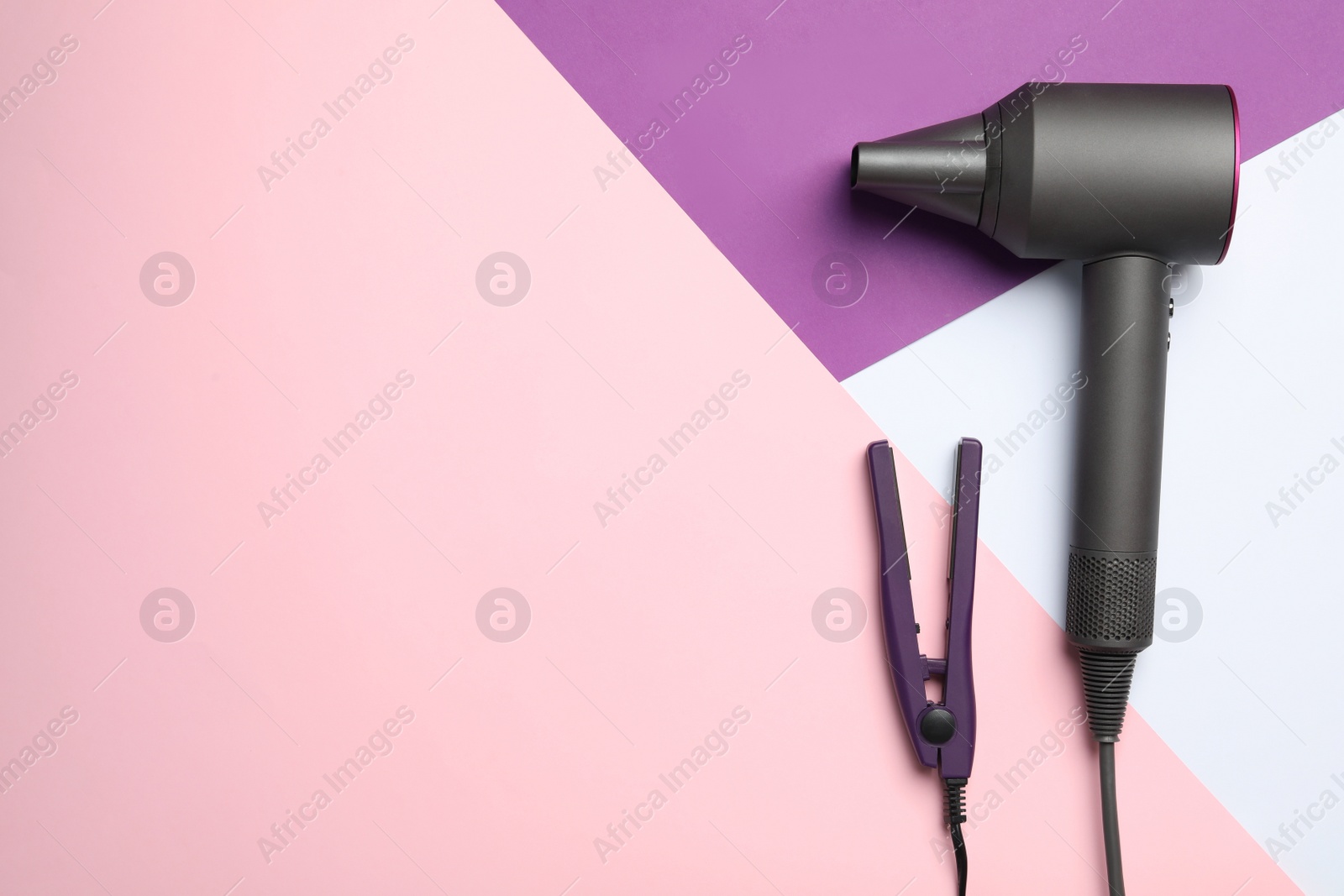 Photo of Hair dryer and iron on color background, flat lay with space for text. Professional hairdresser tool