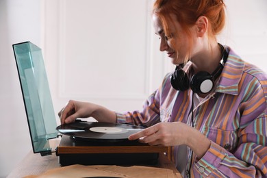 Beautiful young woman using turntable at home