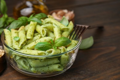 Photo of Delicious pasta with pesto sauce and basil on wooden table, closeup. Space for text
