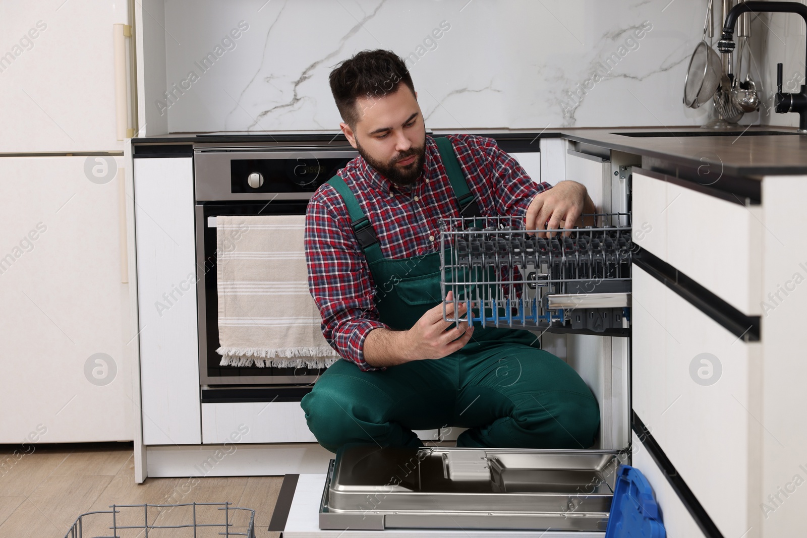 Photo of Serviceman repairing dishwasher cutlery rack in kitchen