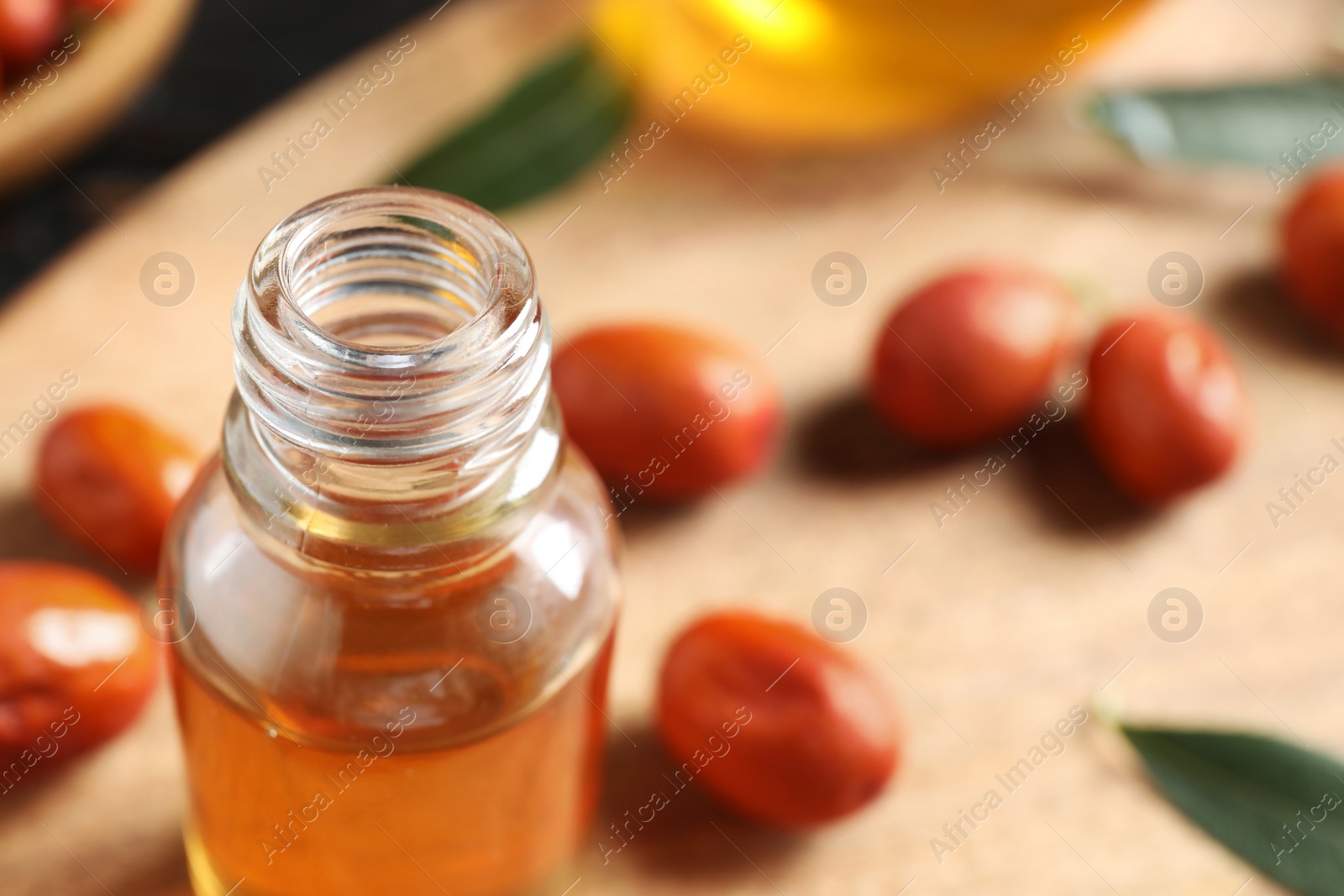 Photo of Glass bottle with jojoba oil on table, closeup. Space for text