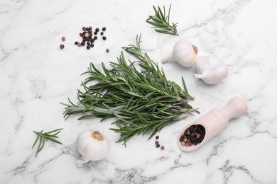Photo of Sprigs of rosemary, garlic and scoop with peppercorns on white marble table, flat lay