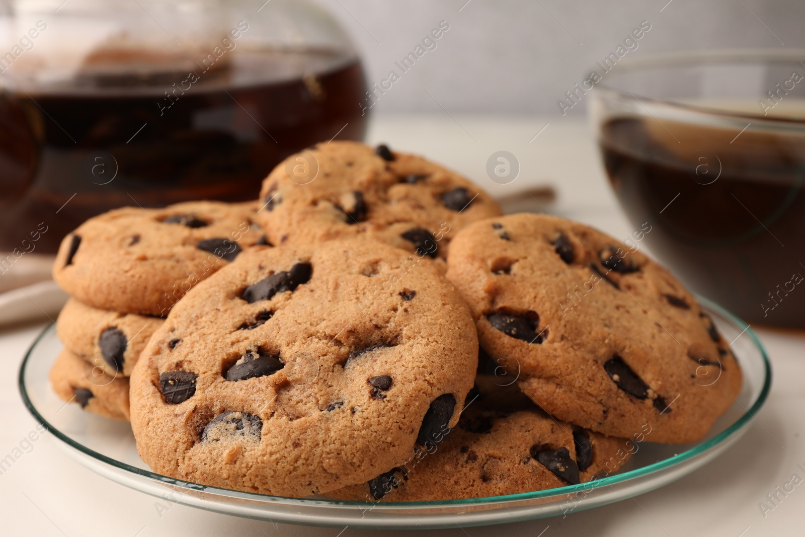 Photo of Delicious chocolate chip cookies and tea on white marble table, closeup