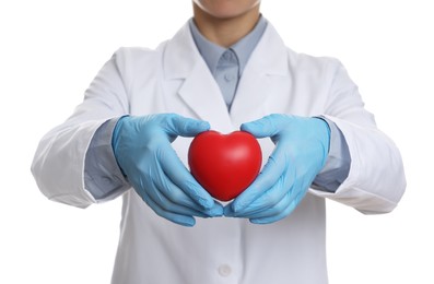 Photo of Doctor wearing light blue medical gloves holding decorative heart on white background, closeup