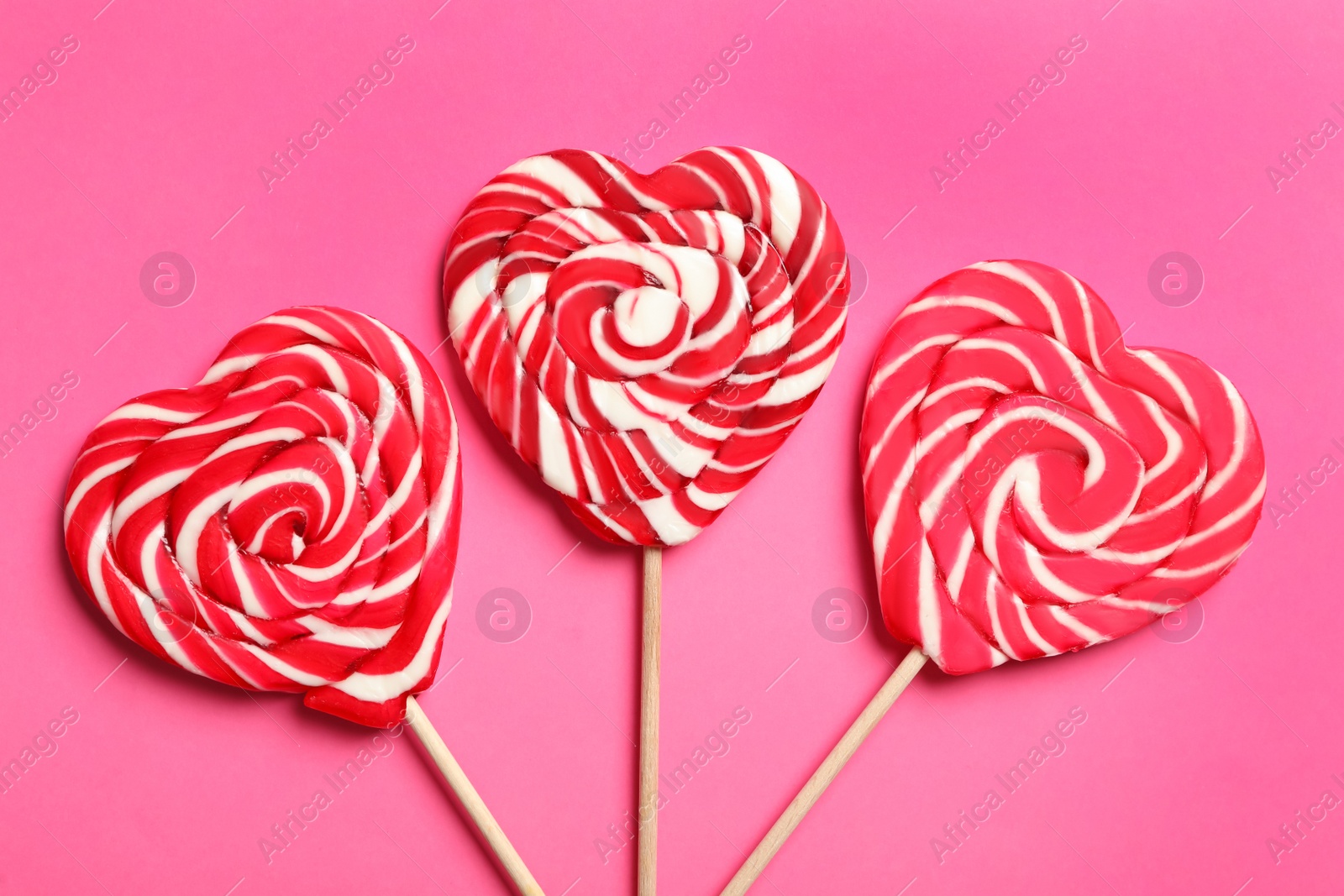 Photo of Sweet heart shaped lollipops on pink background, flat lay. Valentine's day celebration