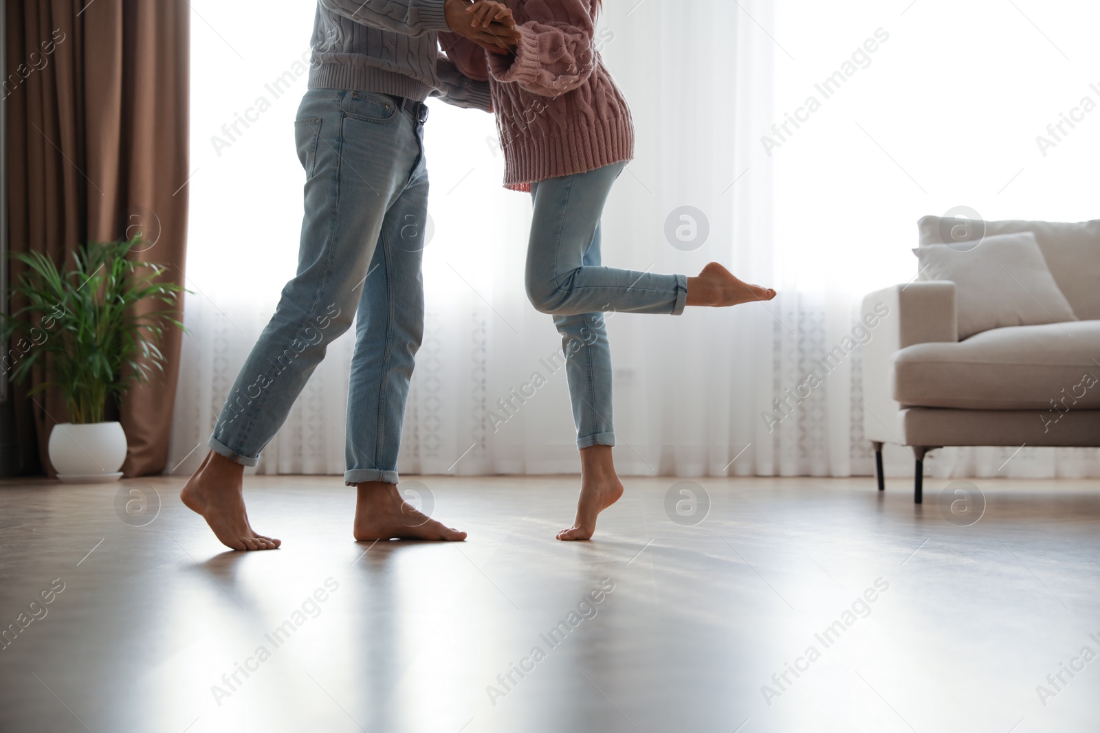 Photo of Couple dancing barefoot in living room, closeup. Floor heating system