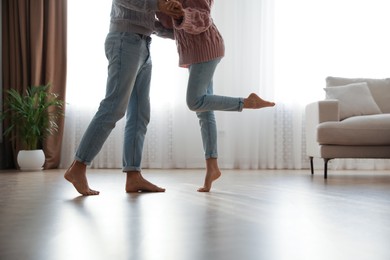 Couple dancing barefoot in living room, closeup. Floor heating system