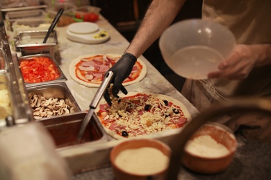 Photo of Man making pizzas at table, closeup view