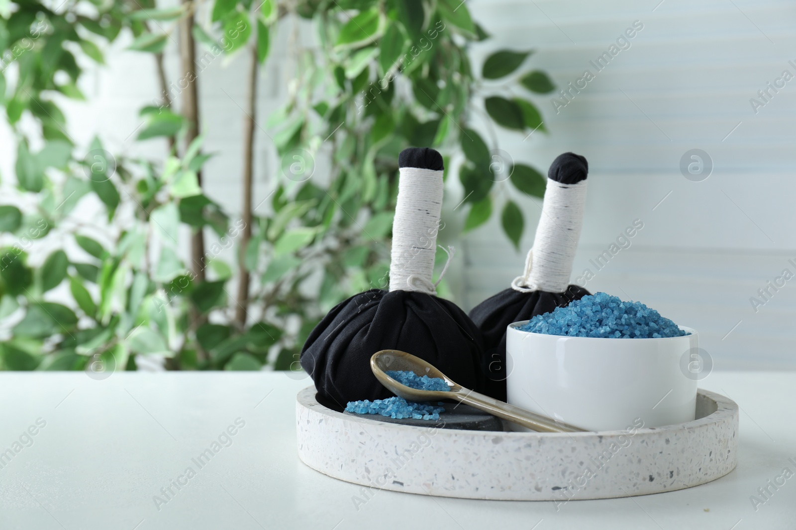 Photo of Blue sea salt and herbal bags on white table indoors, space for text