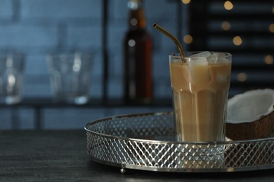 Photo of Glass of iced coffee and coconut on grey table against blurred lights. Space for text