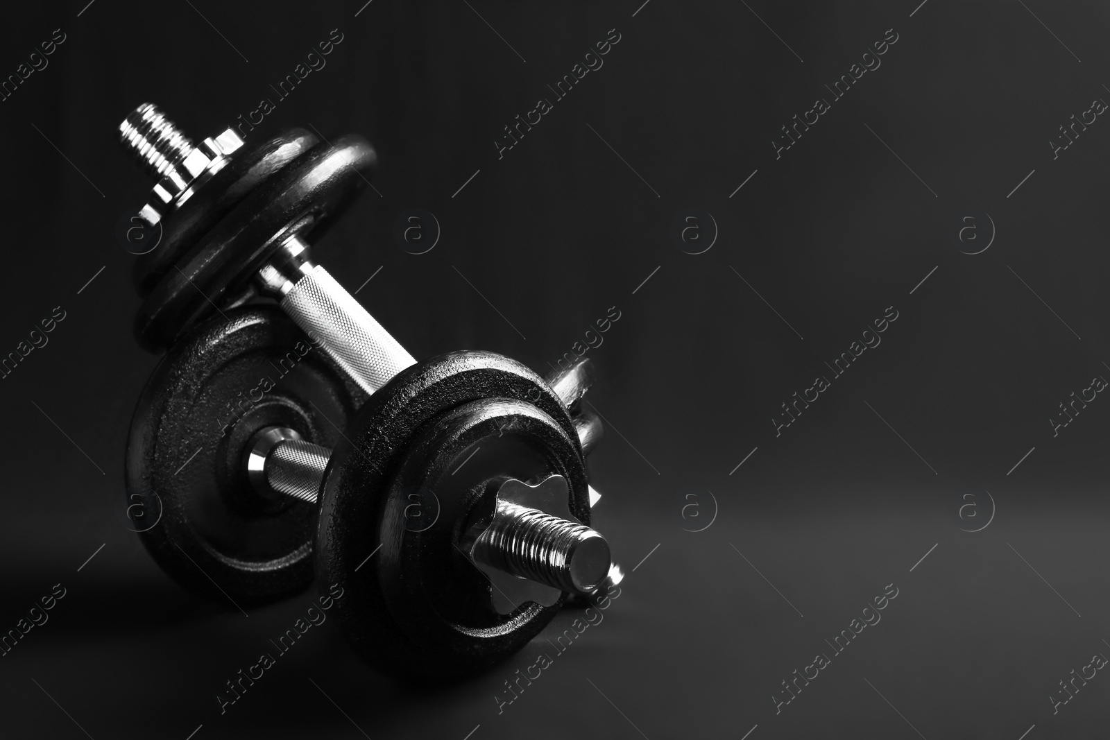 Photo of Pair of adjustable dumbbells on black background. Space for text