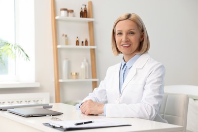 Photo of Portrait of happy dermatologist at white table in clinic
