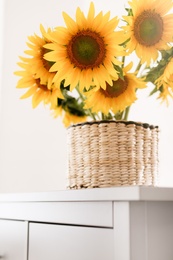 Photo of Beautiful yellow sunflowers on chest of drawers in room