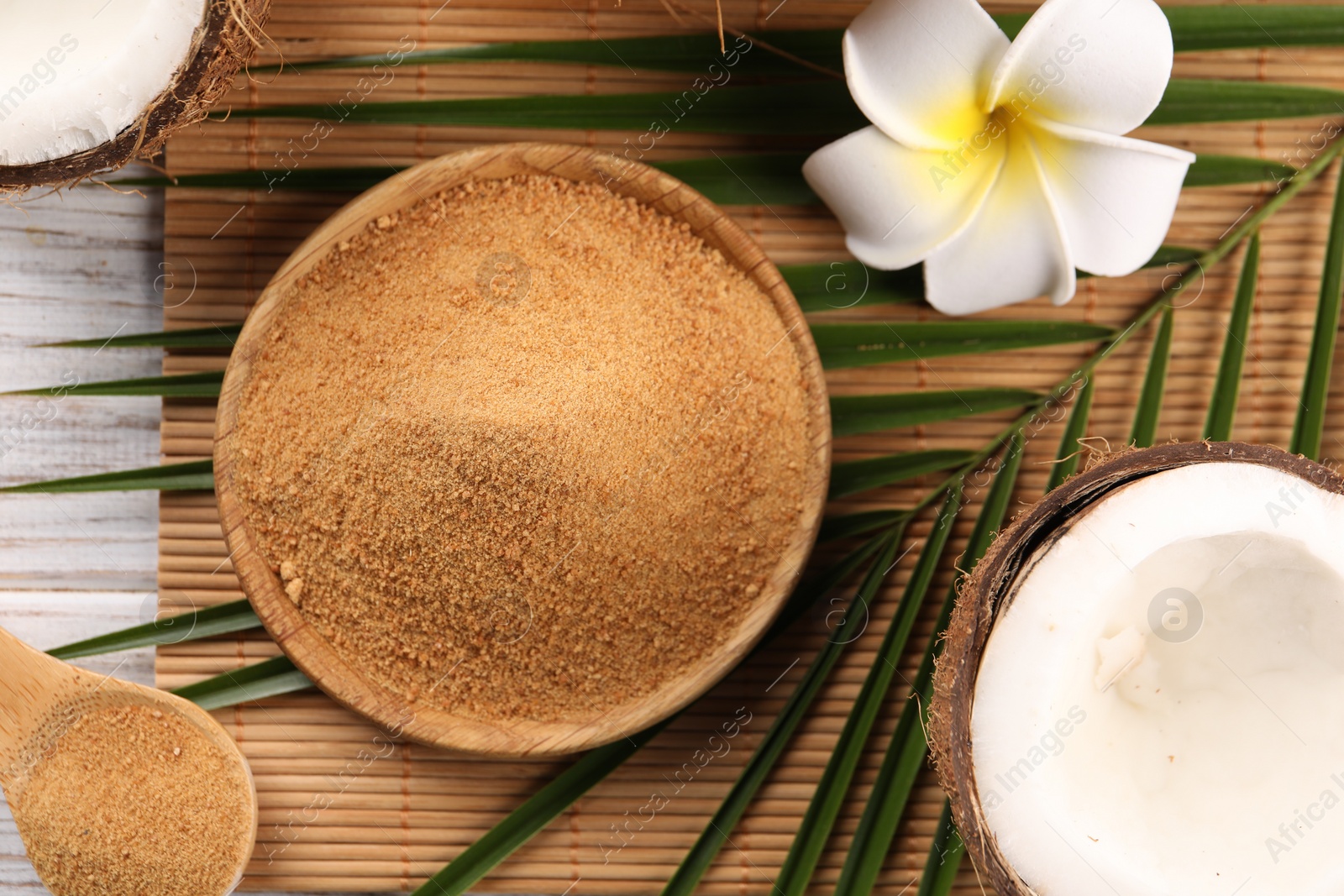 Photo of Coconut sugar, palm leaves, fruits and bamboo mat on table, flat lay