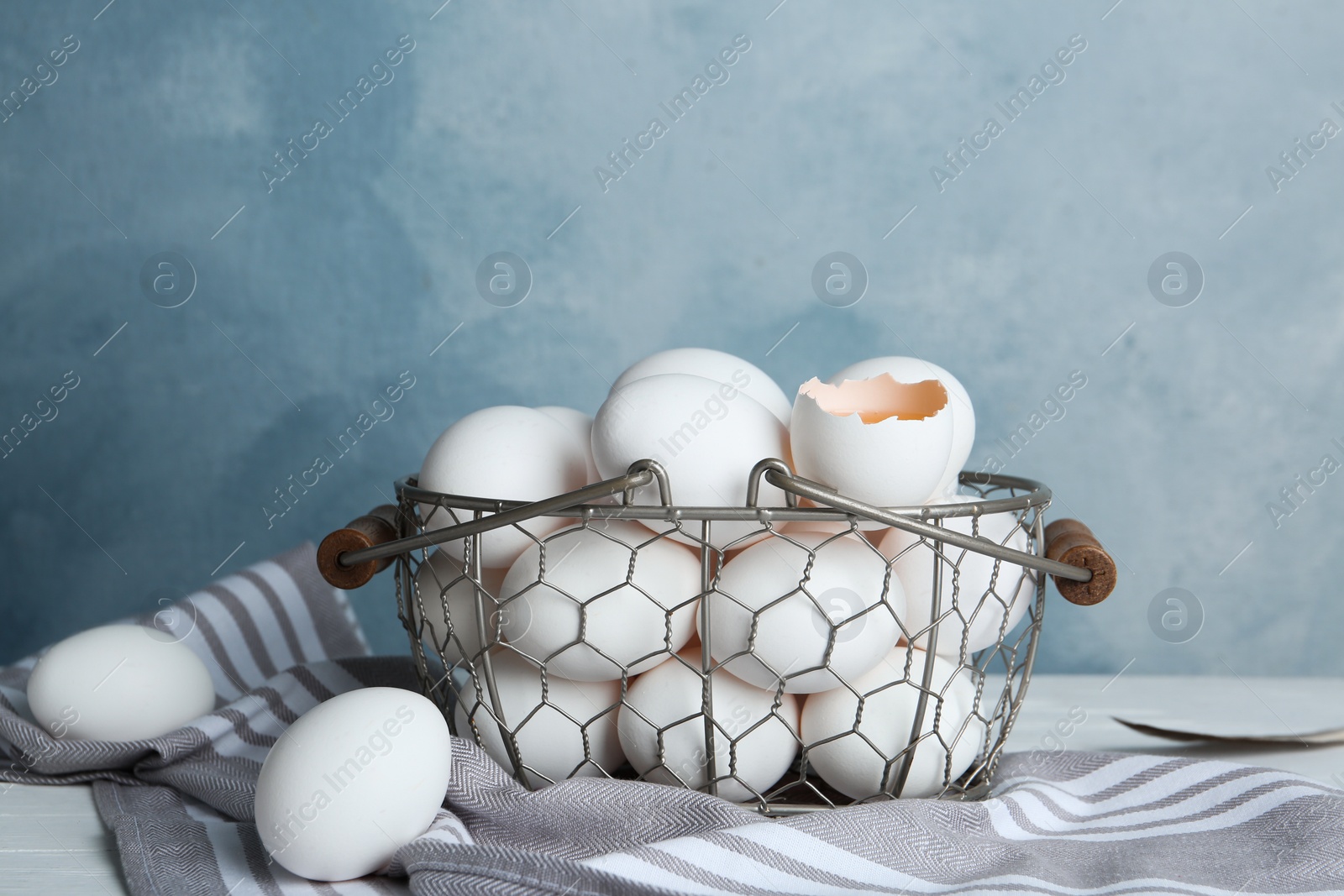 Photo of Chicken eggs in metal basket on table