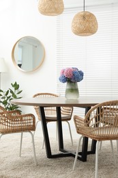 Table, chairs and vase of hydrangea flowers in dining room. Stylish interior