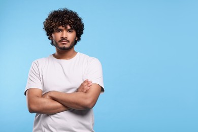 Handsome young man on light blue background, space for text